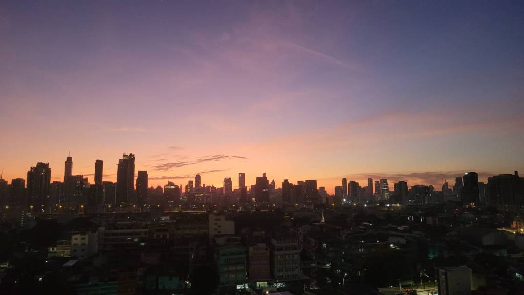 Sunrise on the Bangkok skyline where the skies colours are pink, orange and purple.